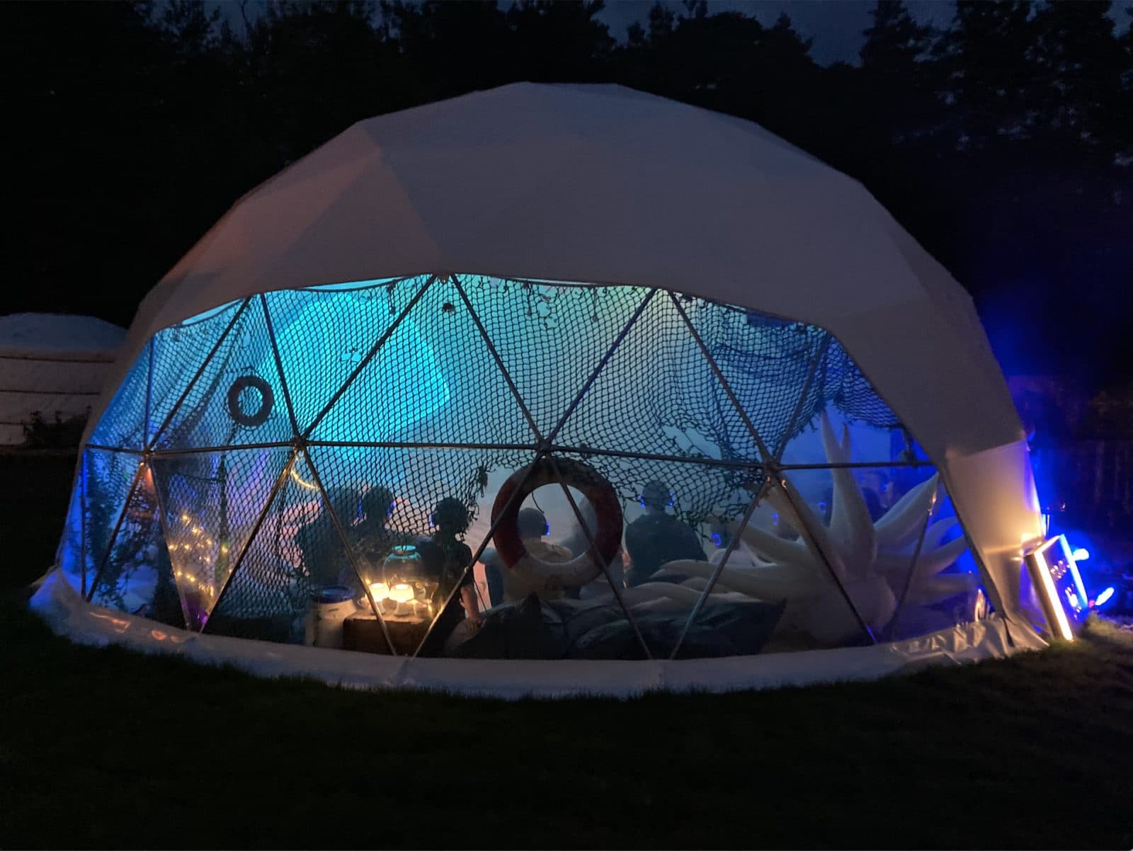 Massarium geodesic dome illuminated at night with performers inside